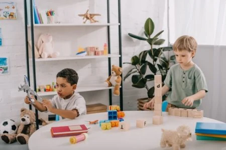 Preschoolers playing with toy plane and wooden blocks