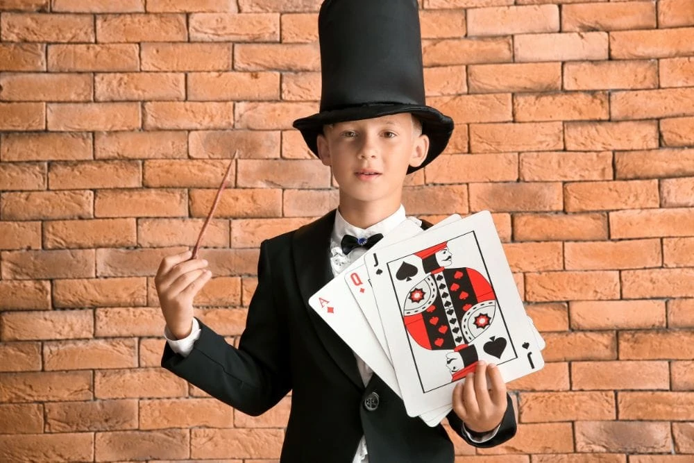 Young magician holding a wand and deck of cards