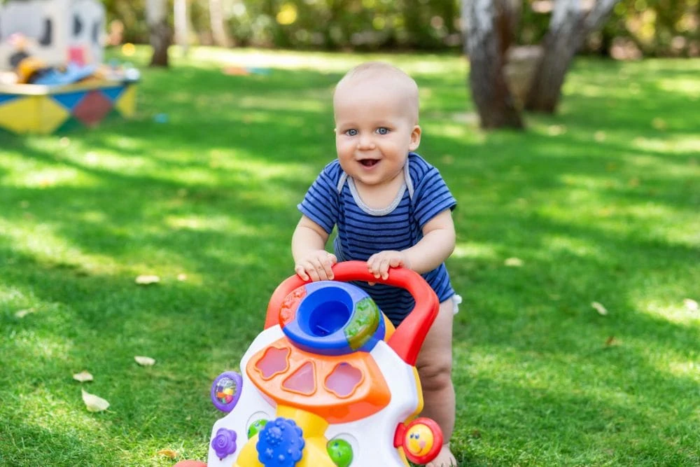 Toddler walking outside with push toy