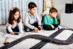 Three children playing with race track