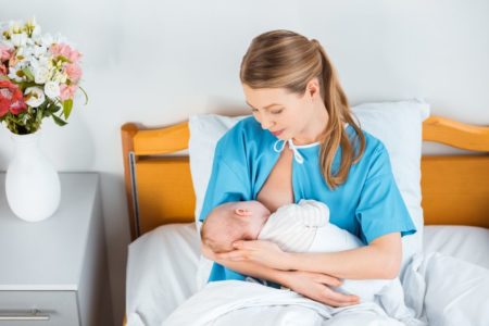 Mom breastfeeding newborn in a hospital bed