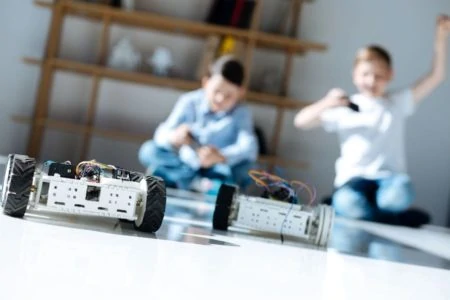 Two young boys racing with robotic cars