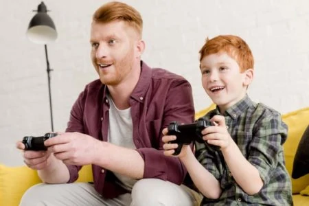 Redhead father and son happily playing video games together