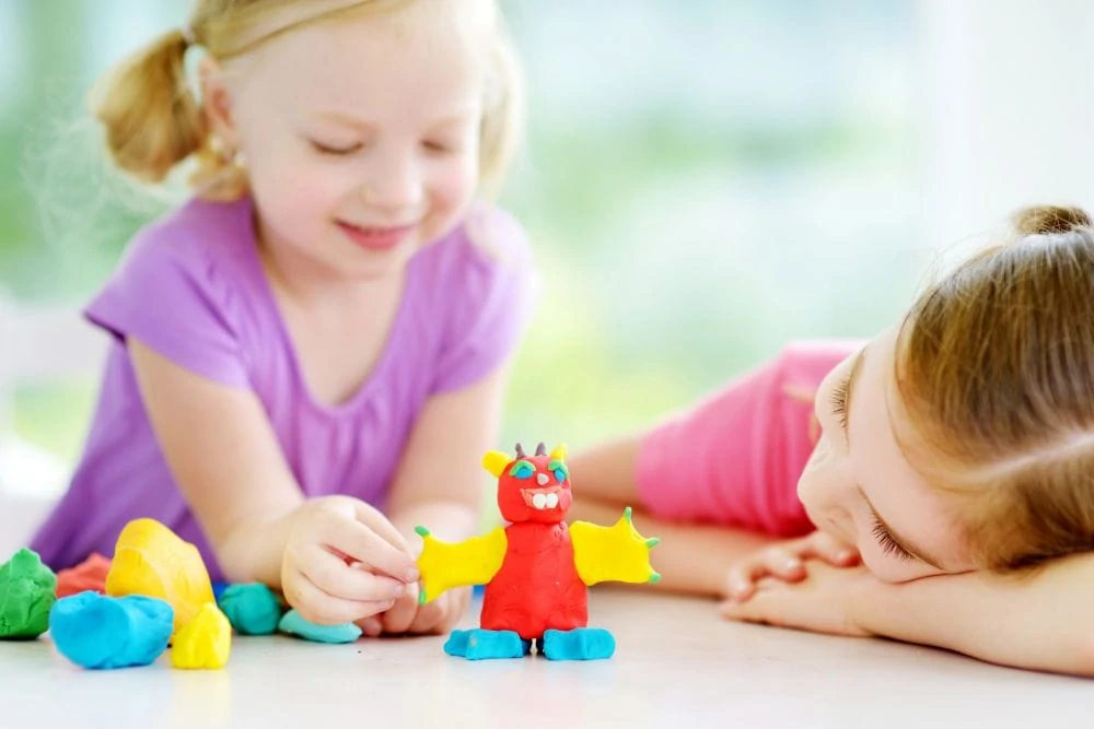 Two little girls playing with clay dough