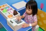 Little asian girl playing with toy cash register