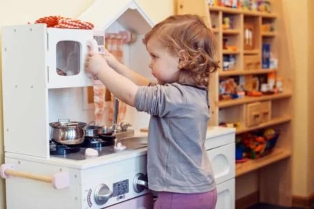 Cute toddler playing with toy kitchen set