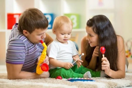 Happy parents and baby playing with musical toys