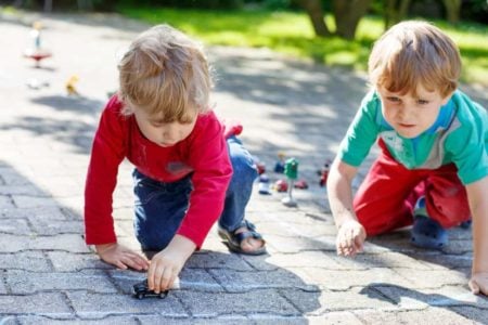 Two young boys playing with toy cars outdoors