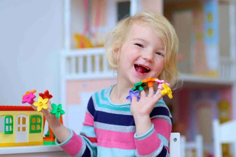 Cute little girl happily playing with flower toys