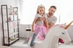Father putting his daughter on top of a unicorn toy