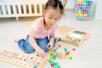 Little asian girl playing with wooden toys