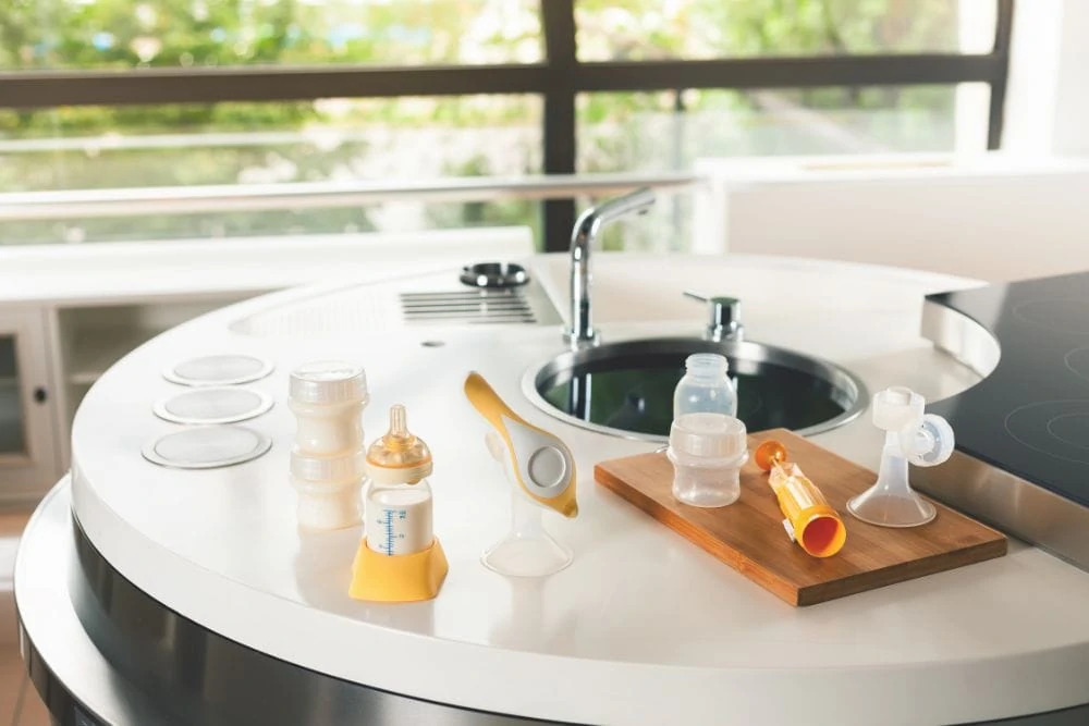 Breast pump and baby bottles laying on the sink counter