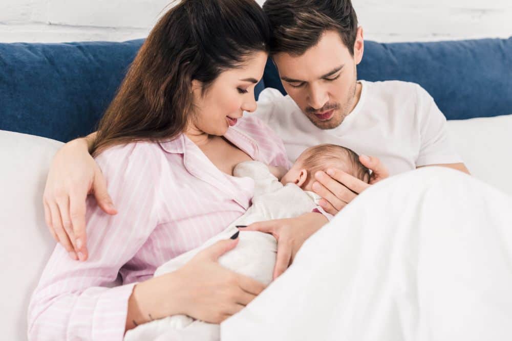 New parents breastfeeding baby in bed