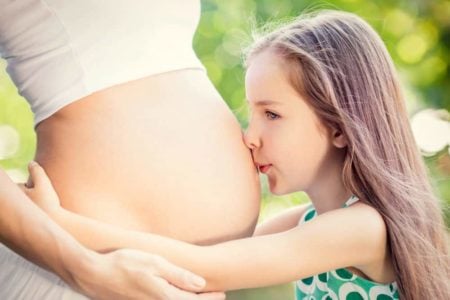 Little girl kissing her pregnant mommy's belly