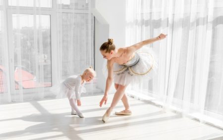 Beautiful ballerina teaching a toddler ballet in a studio
