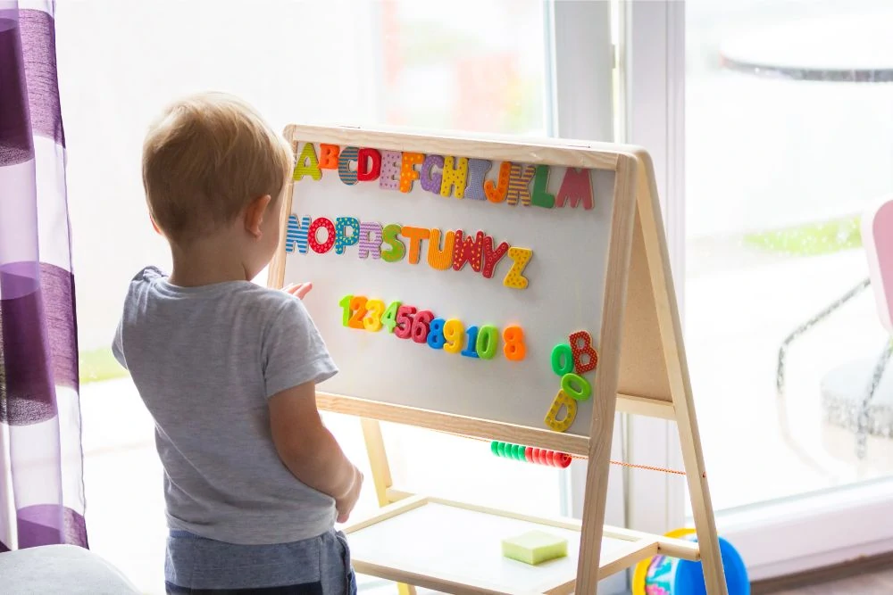 Toddler learning the alphabet on a whiteboard