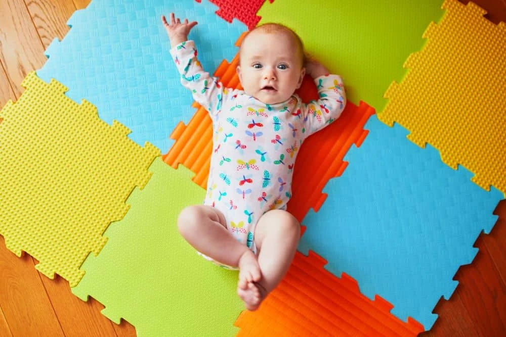 Cute baby lying on a colorful play mat