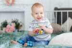 Smiling baby boy in stripes playing with a rattle
