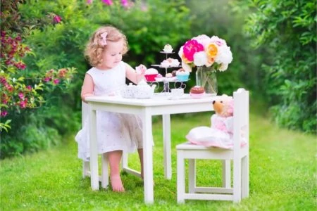 Beautiful little girl having tea party outside with her teddy
