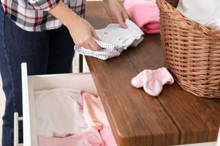 folding baby clothes on top of drawer