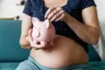 Pregnant woman saving money in a piggy bank