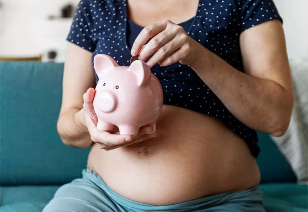 Pregnant woman saving money in a piggy bank