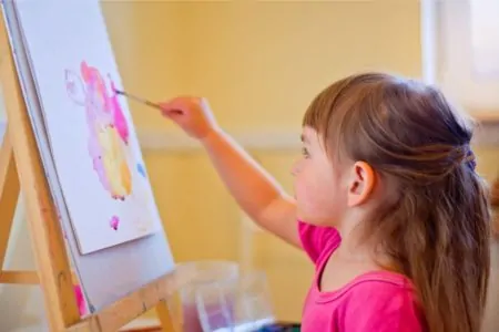 Cute little girl painting on an easel