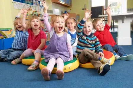 Children in preschool raising their hands