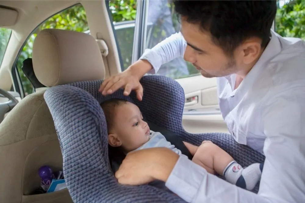Father putting his baby in a rear facing car seat