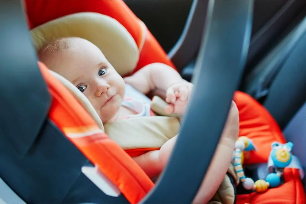 Cute infant holding his feet in an infant car seat