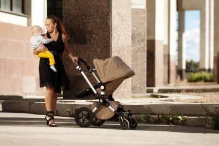 Fashionable modern mother pushing a luxury stroller