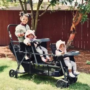Three children sitting in a triple stroller