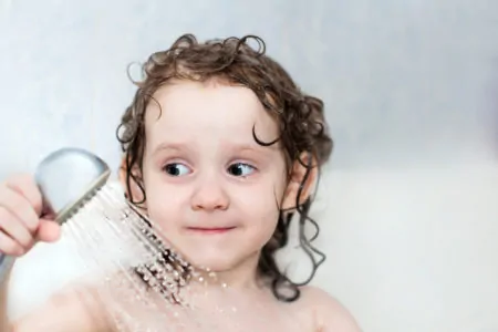 Little girl using a kids shower head
