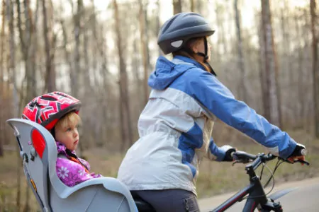 Mother riding a bicycle with daughter in a bike seat