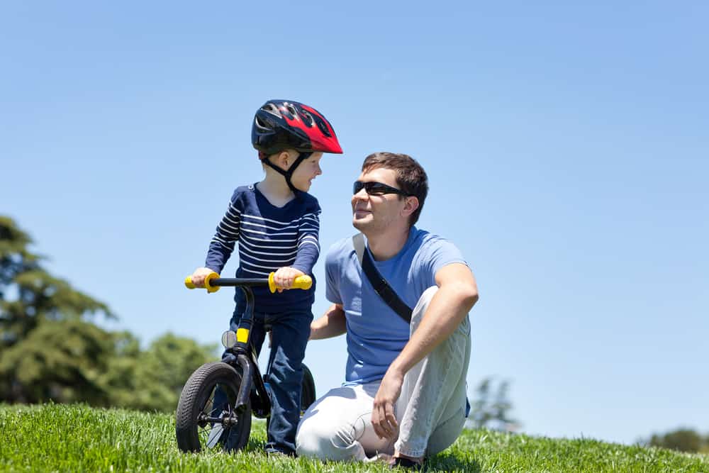 Father teaching son how to ride a balance bike