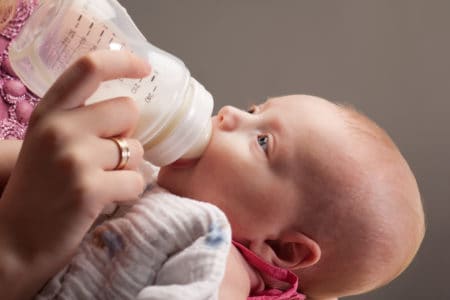 Newborn drinking milk from a bottle