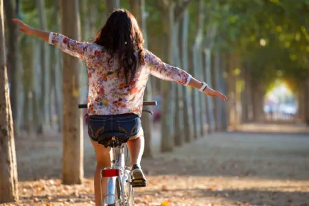 Young girl riding a bike with outstretched arms