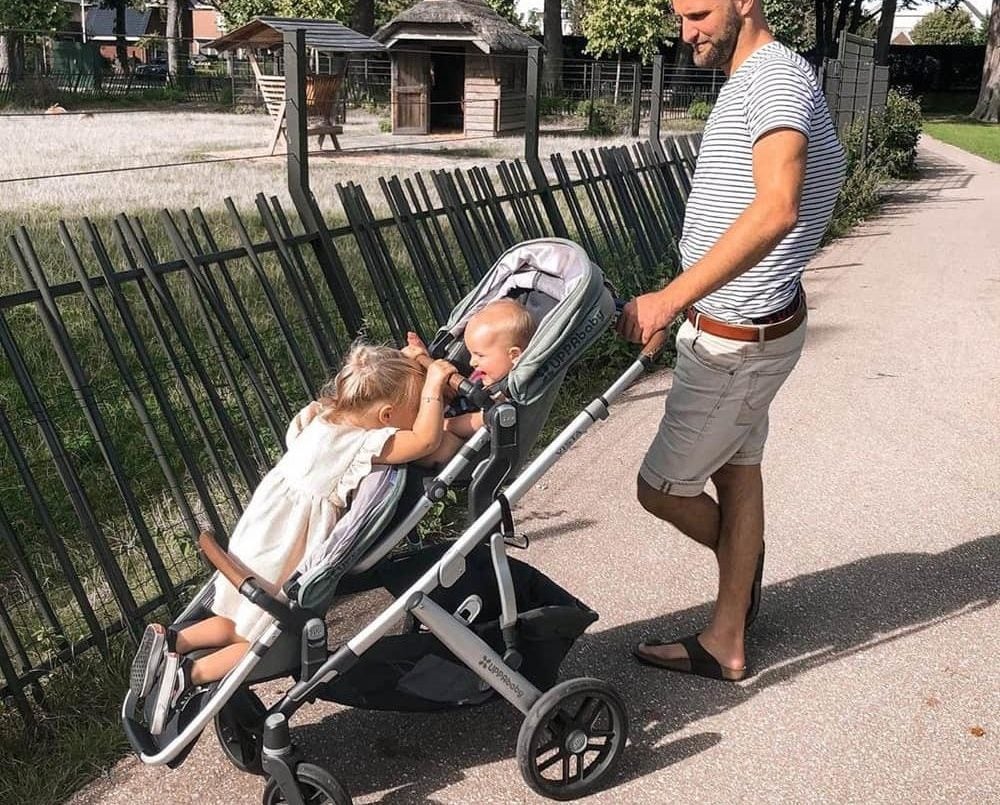 Dad walking his children outside with a stroller and board