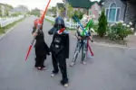 Three boys playing with lightsabers in star wars costume