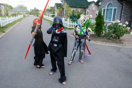 Three boys playing with lightsabers in star wars costume