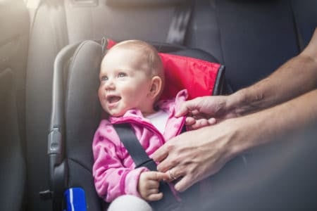 Happy baby strapped safely in a car seat