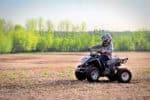 Young boy driving an ATV on a field