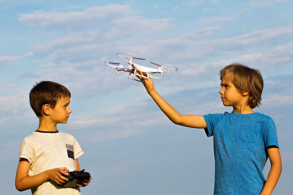 Kids playing with a drone outdoors.