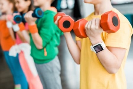 Kids with fitness tracker lifting weights