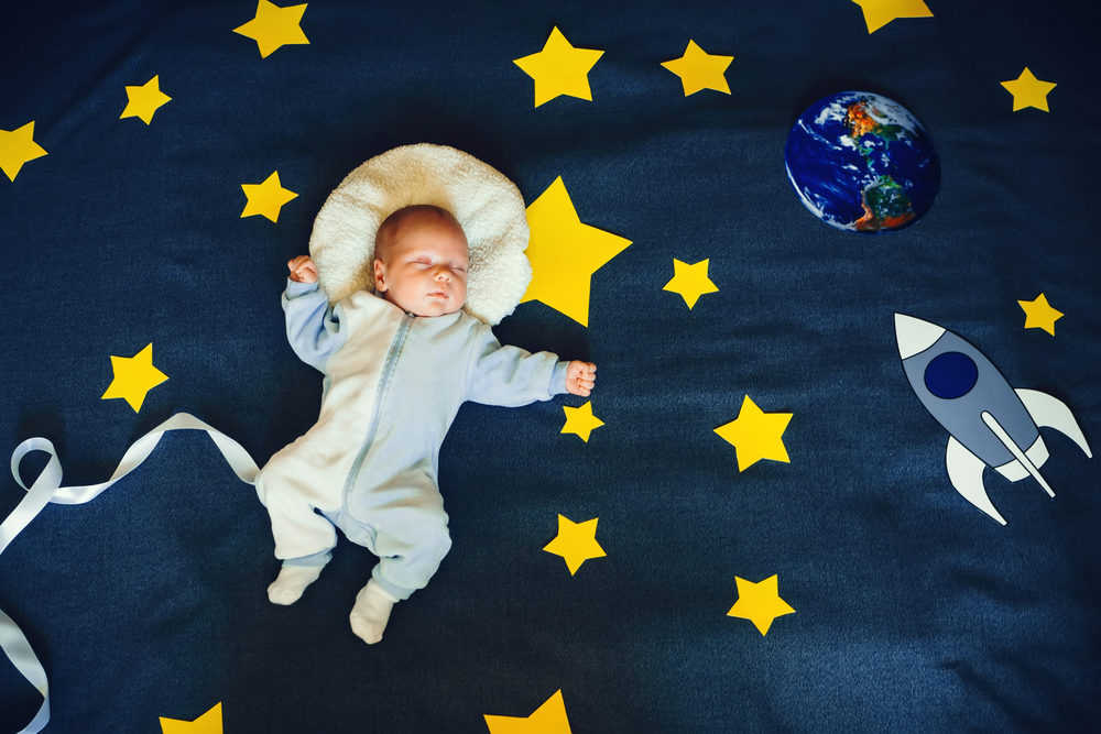 Baby boy sleeping on space-themed blanket
