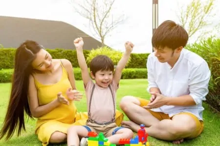 Parents cheering on young son while playing outside