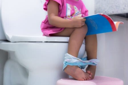 Toddler toilet training while reading a book