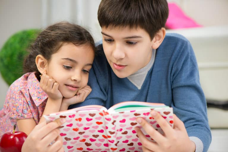 Big brother and little sister reading a book together