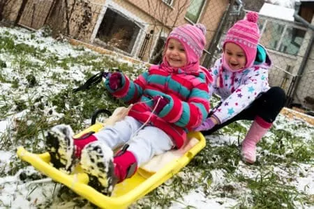 Little kids playing outside with snow sleds