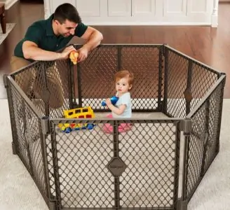 Toddler playing inside a baby fence